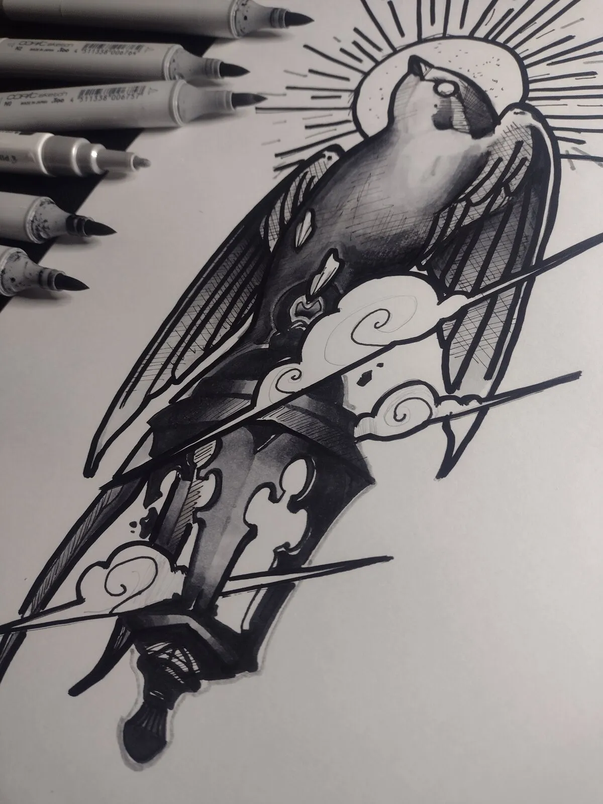 Desenho a nanquim em preto e branco de uma andorinha de asas abertas com uma auréola de raios atrás da cabeça, sobre uma lanterna entre nuvens espirais, com canetas Copic ao lado