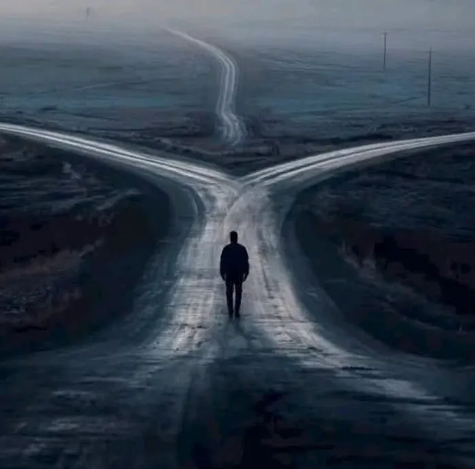 Um homem sozinho, de costas, caminhando por uma estrada de terra que se divide em três caminhos, numa paisagem fria e enevoada